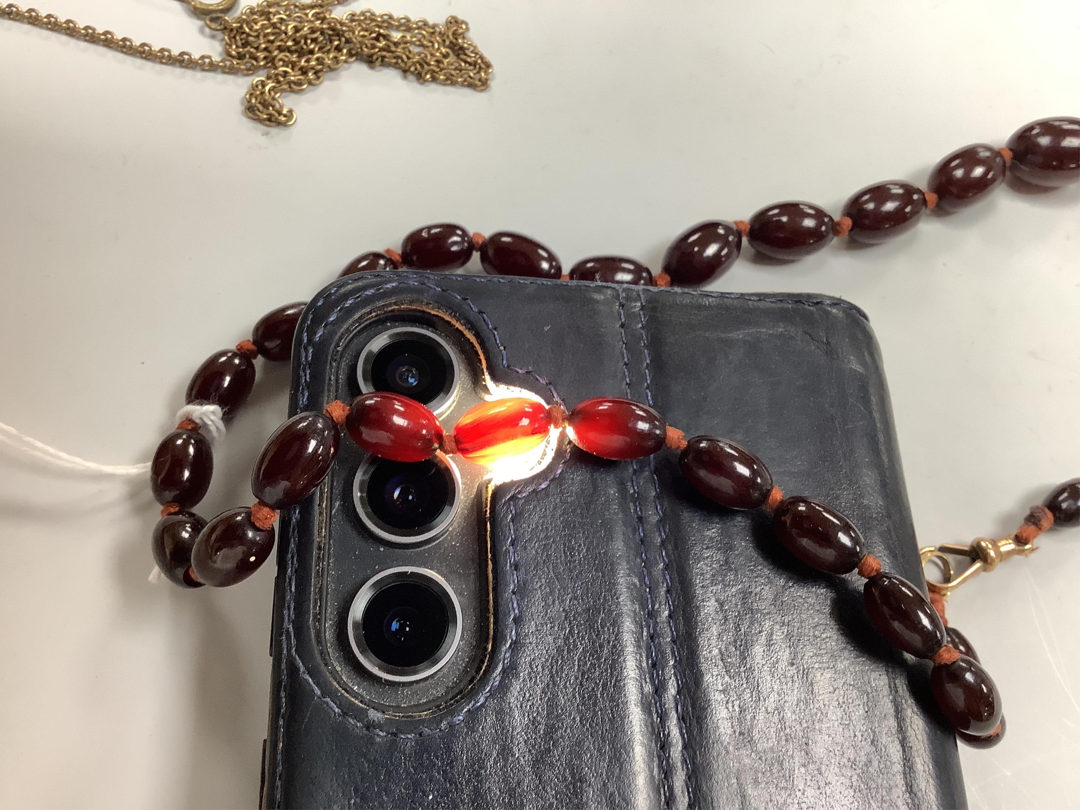 A cherry bakelite 'amber' necklace and pendant, comprising: a necklace composed of cherry-coloured bakelite beads measuring approximately 10 - 26mm, length 90cm, gross weight 72 grams; and a drop-shaped pendant, length 5